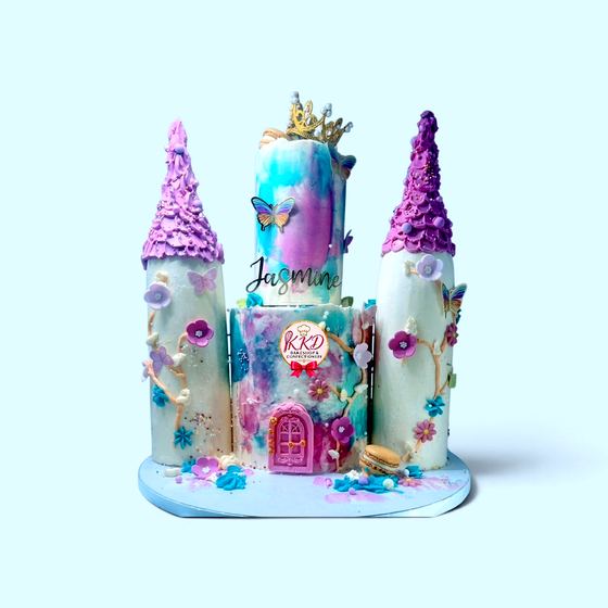 A sculpted castle cake with turrets and a personalised name