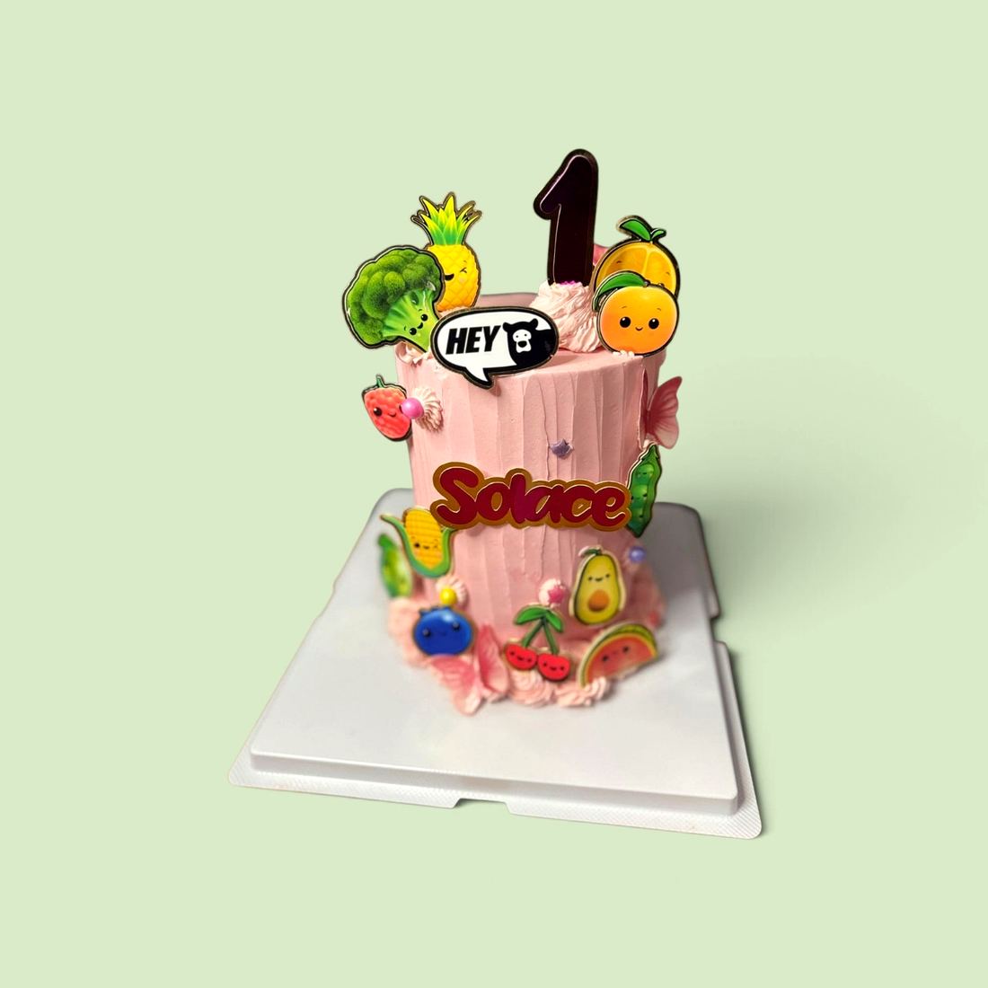 A first birthday cake decorated with sugar fruit and a number topper