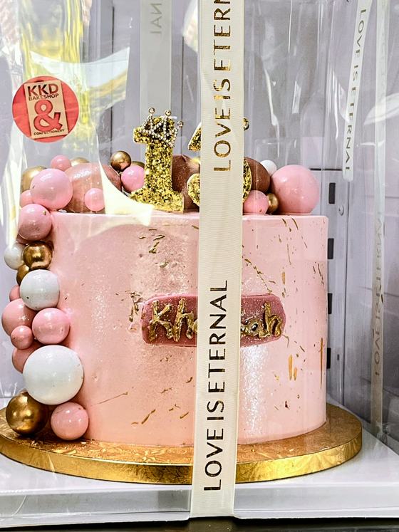 Pink and gold first birthday cake with a balloon hoop